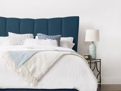 Navy blue channel tufted queen bed with plush velvet upholstery and sleek wooden legs.