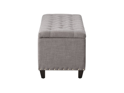 Light grey tufted storage ottoman with wooden legs and soft fabric upholstery.