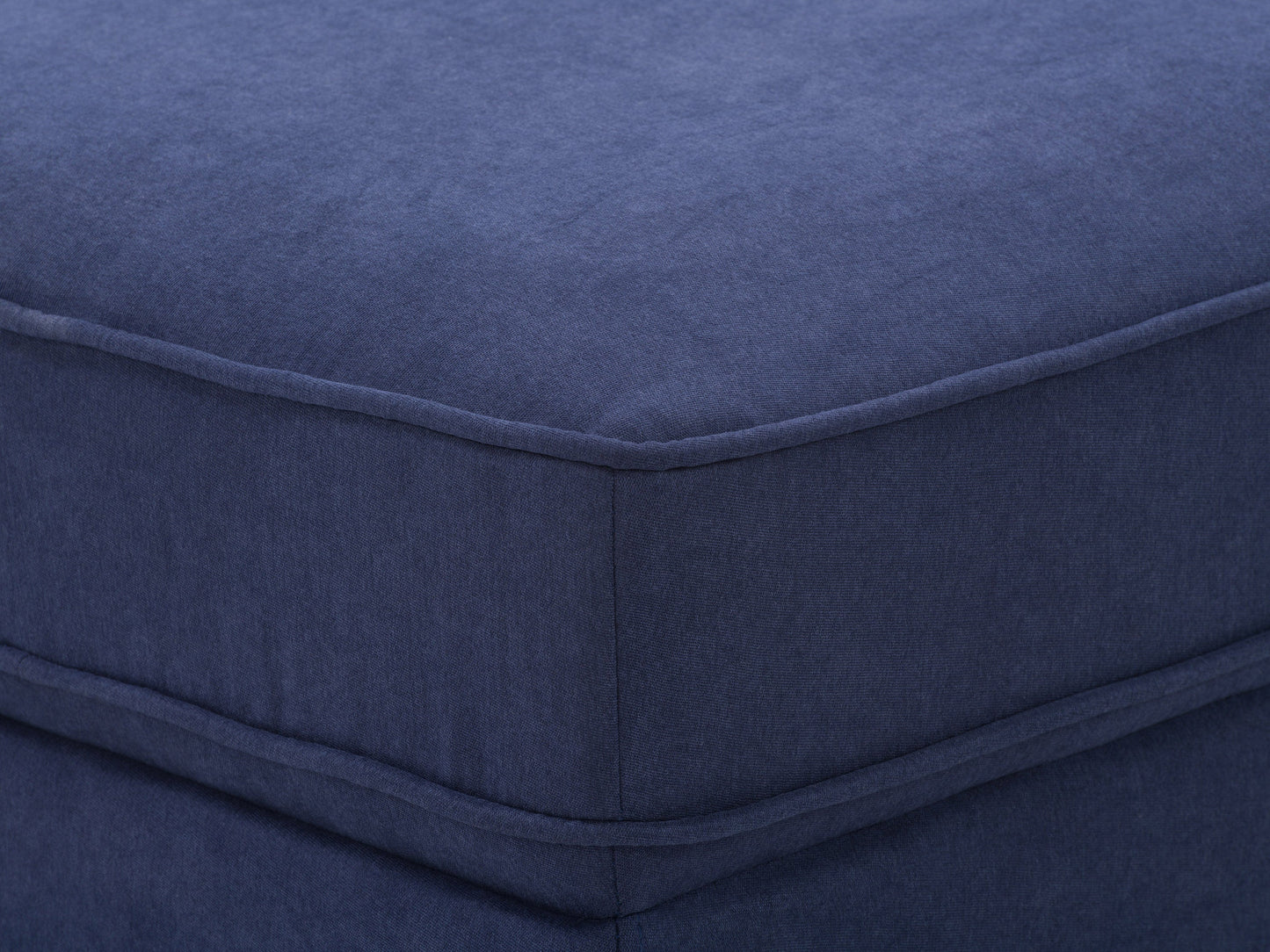 Navy blue mid-century modern ottoman with tufted fabric and wooden legs.