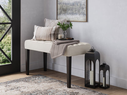 White leather bench with sleek wooden legs, minimalist design, and tufted seat cushion.