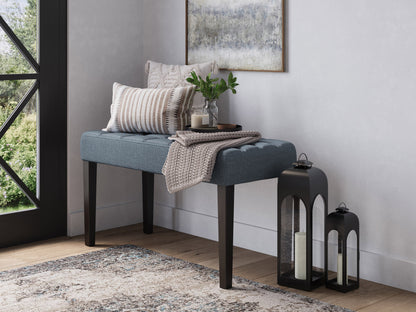 Blue entryway bench with tufted fabric, wooden legs, and a modern design.