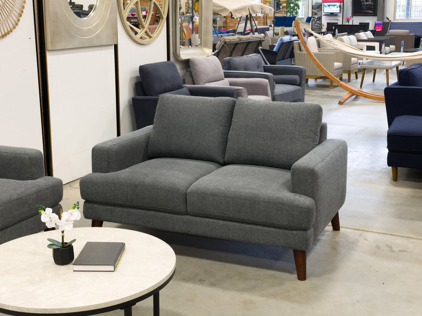 Dark grey modern loveseat with tufted cushions and wooden legs, perfect for contemporary living rooms.