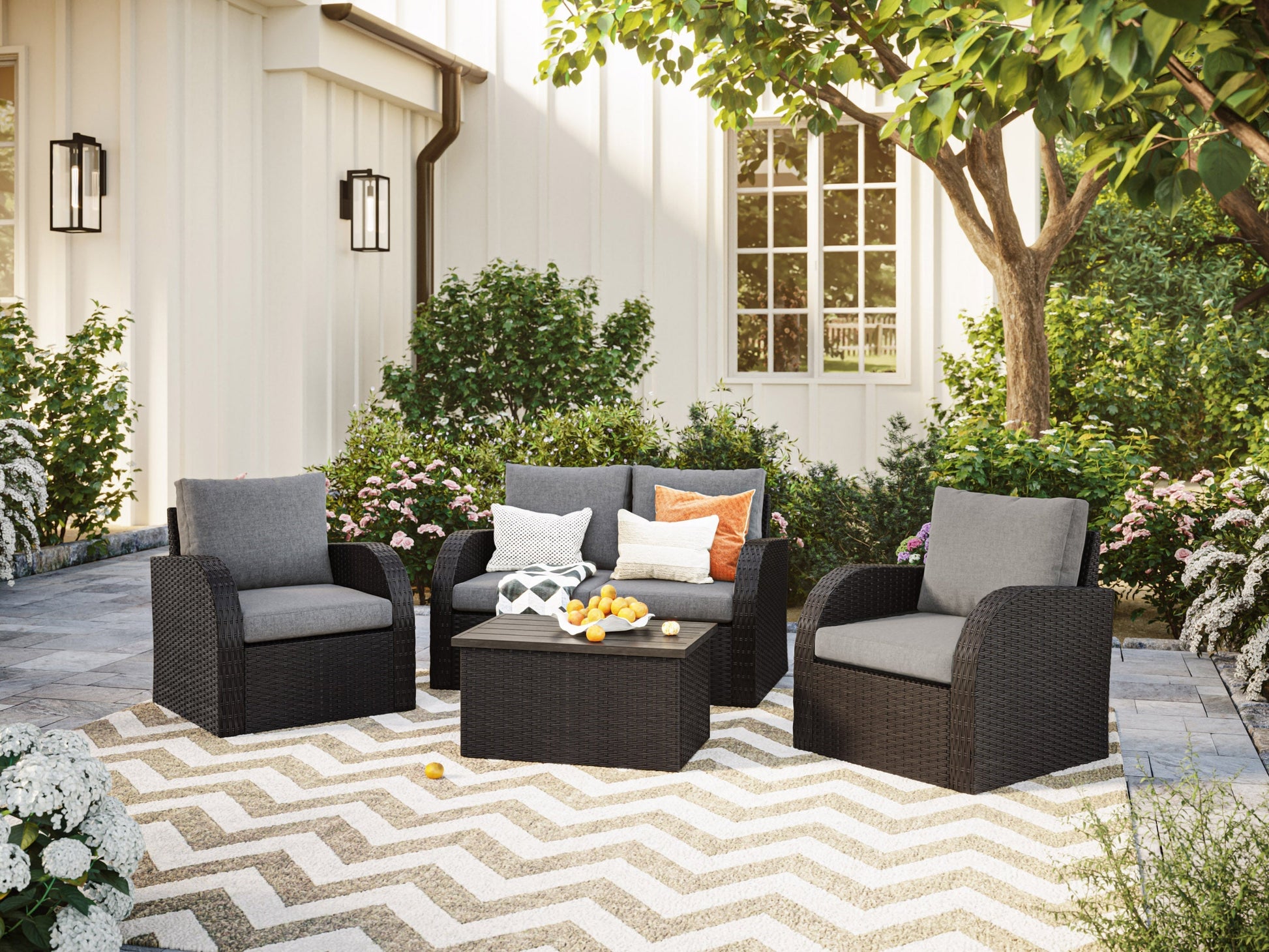 Grey outdoor loveseat set with cushions, coffee table, and ottomans, featuring a weather-resistant wicker design.