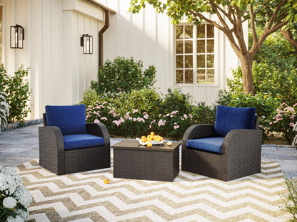 Blue outdoor wicker patio set with cushioned chairs and glass-top table on wooden deck.