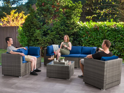 Outdoor patio conversation set, 7-piece, featuring a sleek gray wicker sofa with plush white cushions, a matching coffee table with a glass top, and additional chairs, perfect for modern outdoor lounging.