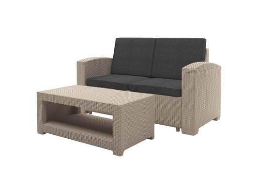 Outdoor wicker loveseat with beige cushions, brown rattan frame, and two matching throw pillows. Ideal for patio conversation sets, this weather-resistant loveseat offers comfort and style for outdoor living spaces.