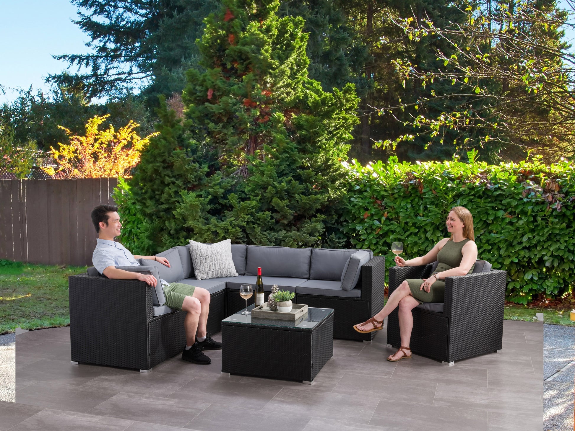 Outdoor patio sectional set, 7 pieces, featuring gray cushions and a dark brown wicker frame, including a glass-top coffee table and modular design for customizable seating arrangements.